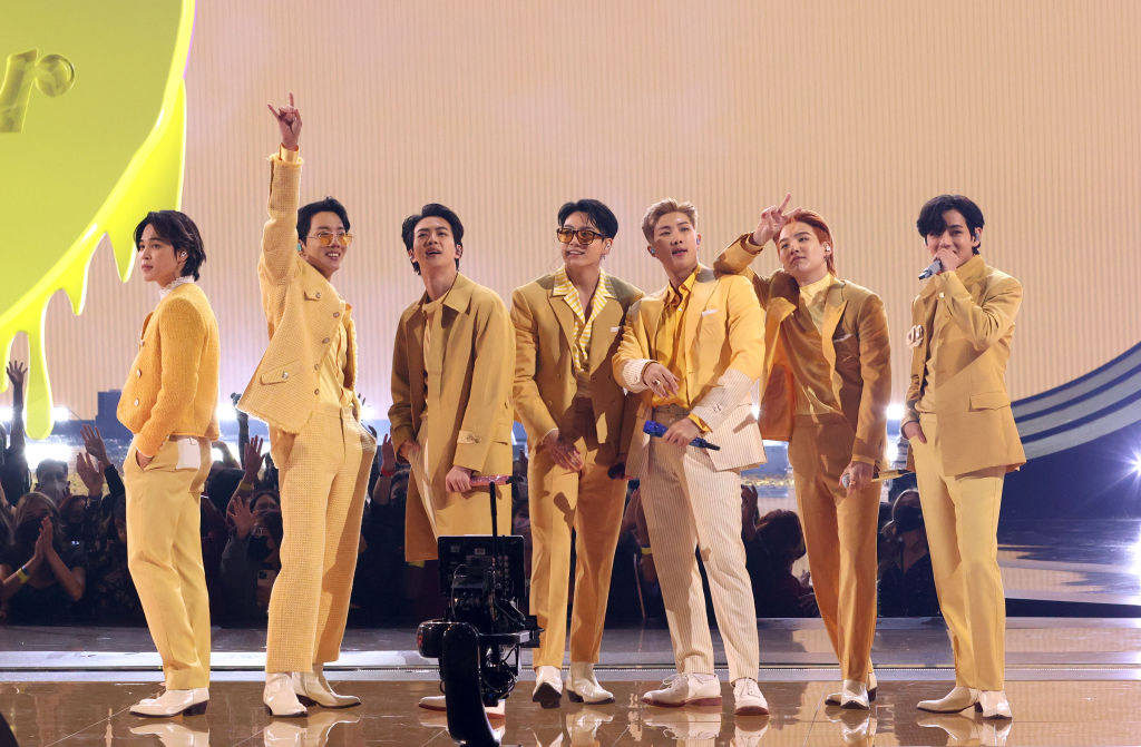 BTS performing on stage in coordinated gold outfits during a live show