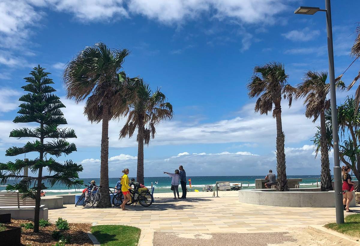 Kingscliff foreshore with palm trees, cyclists and beachgoers overlooking the ocean on a sunny day