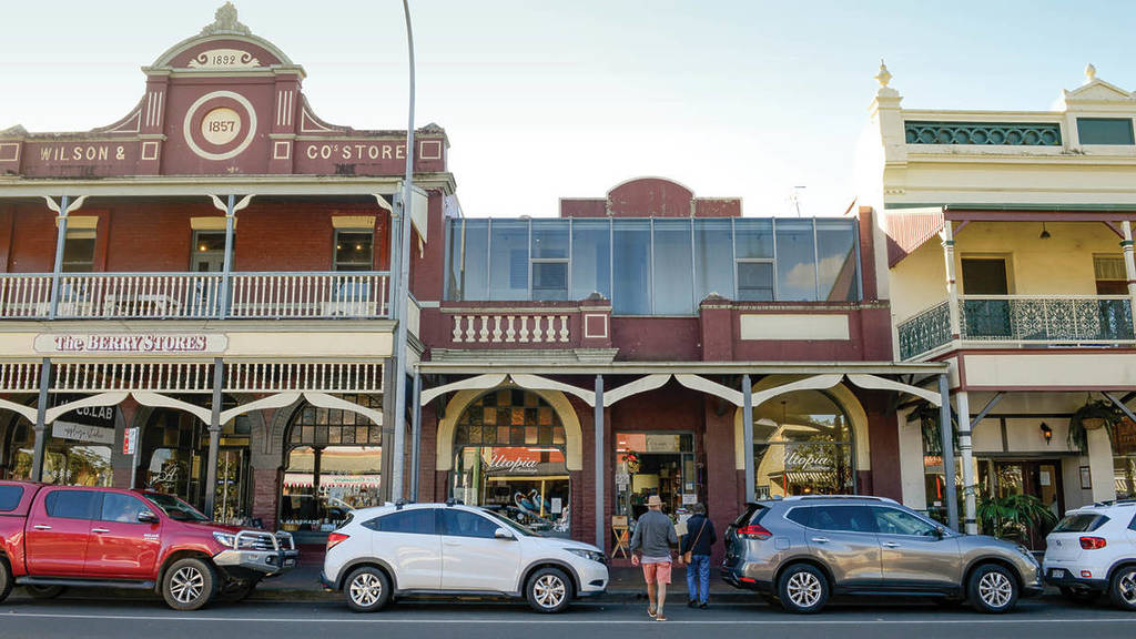 Heritage shopfronts in Berry, NSW with parked cars, historic balconies and people walking past boutiques