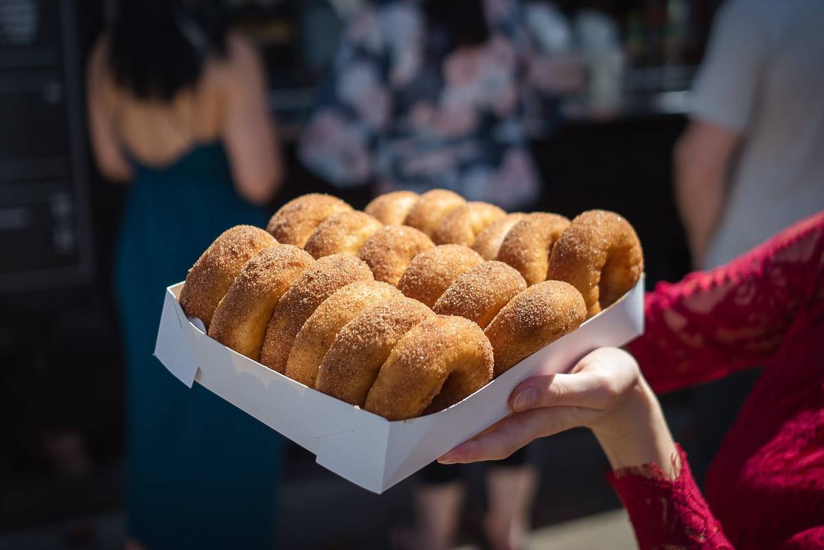 A box of sugar-coated doughnuts at a bakery in regional NSW with customers blurred in the background