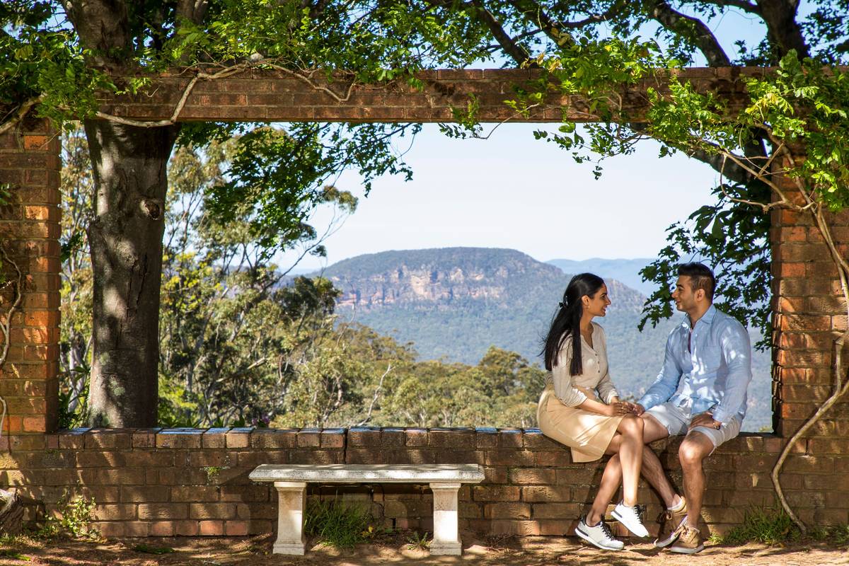 Couple sitting at Leura Cascades picnic area, with Blue Mountains views in the background