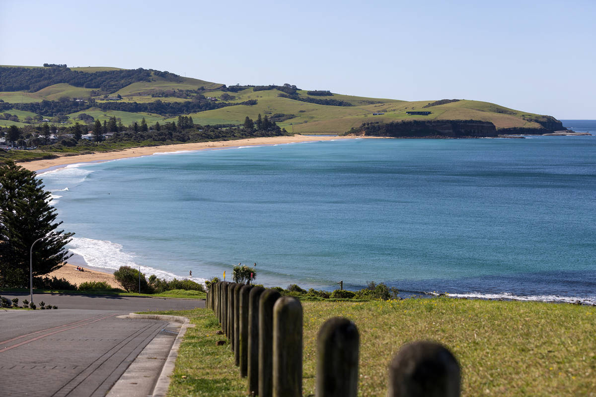 View over Werri Beach from the headland, with rolling green hills, coastline and ocean below