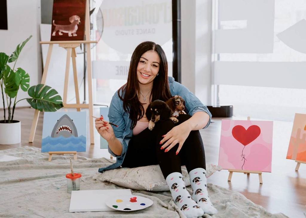 woman painting surrounded by puppies