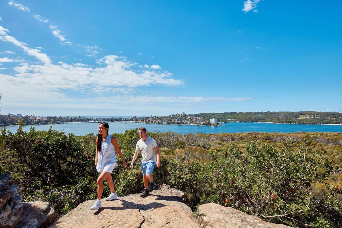 Hikers on a rocky lookout along the Spit to Manly Walk with views across North Harbour and Manly