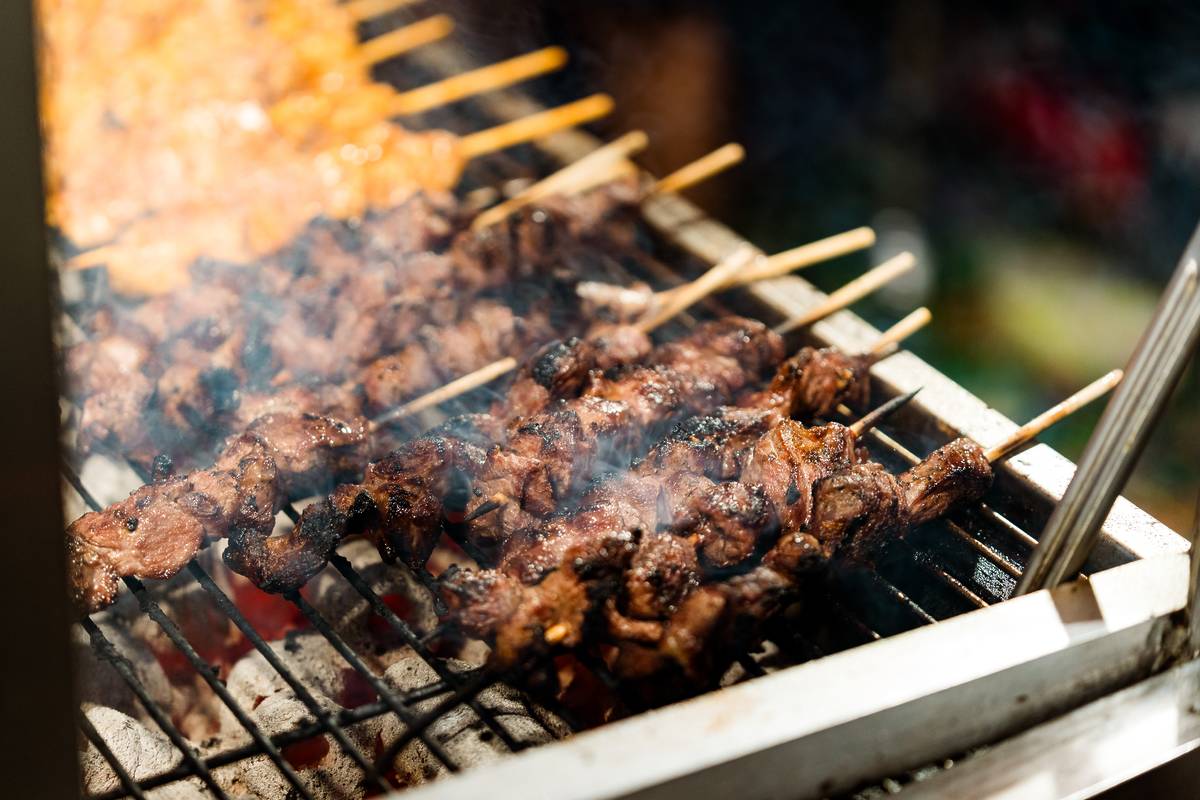 Grilled meat skewers smoking over charcoal at Lakemba Nights Ramadan night market in Sydney
