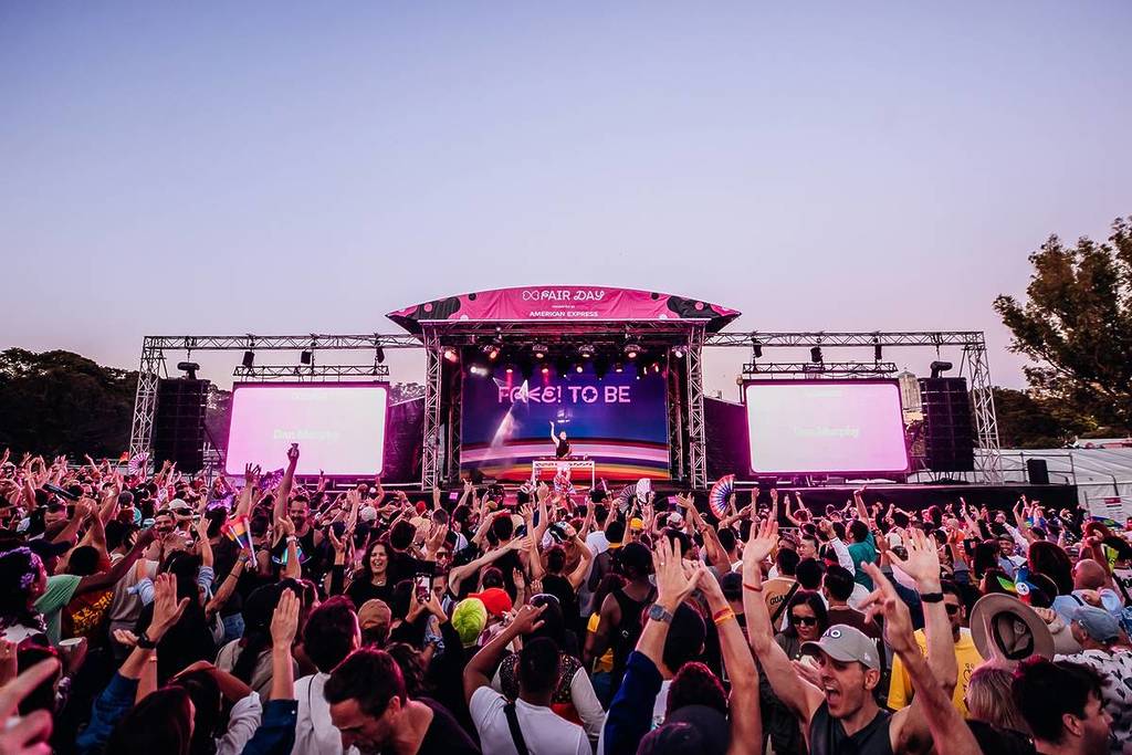 Crowds raise their hands in celebration for a DJ performing on the main stage at Fair Day.
