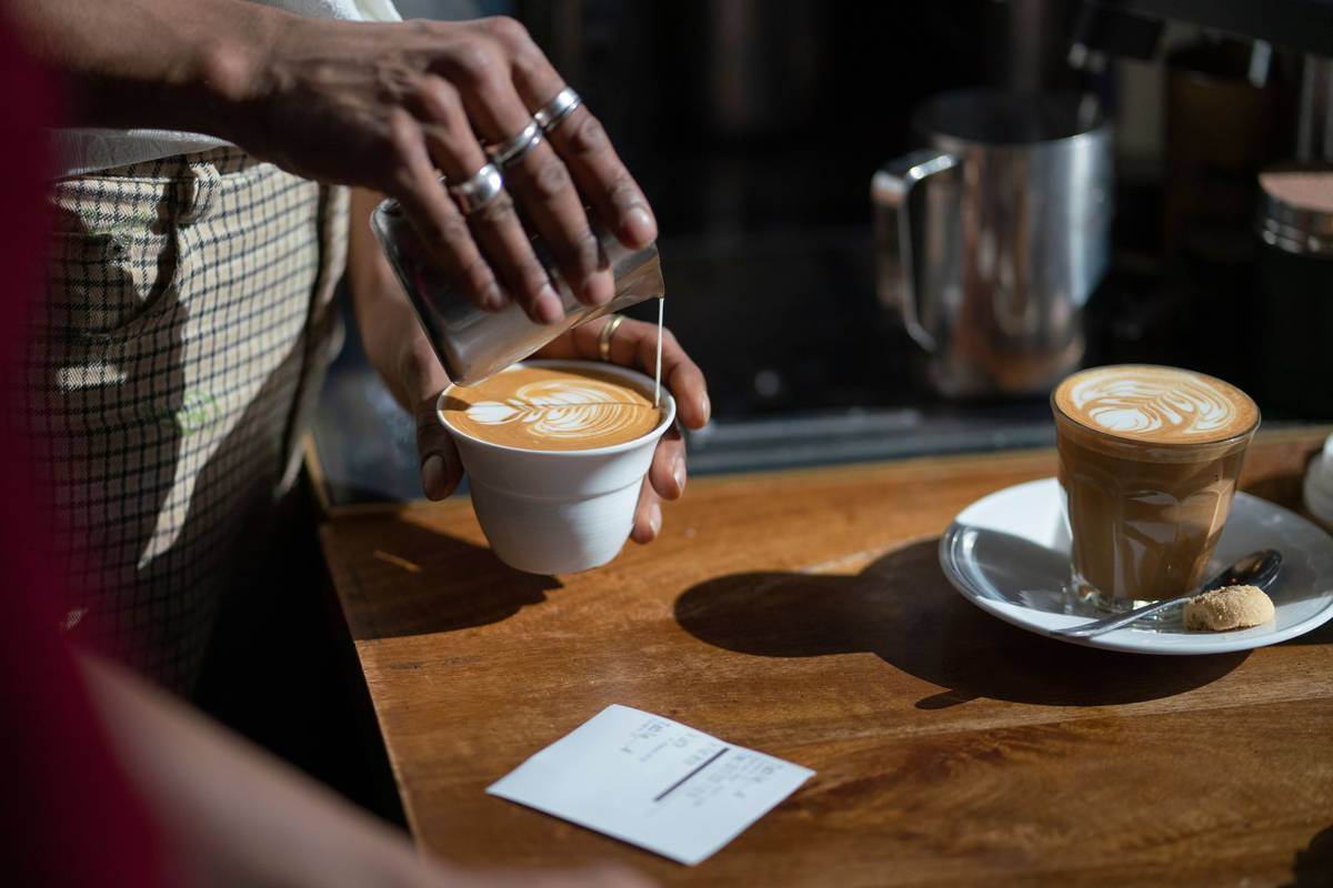 Barista pouring milk to create latte art in a freshly made coffee at a coffee shop in Sydney