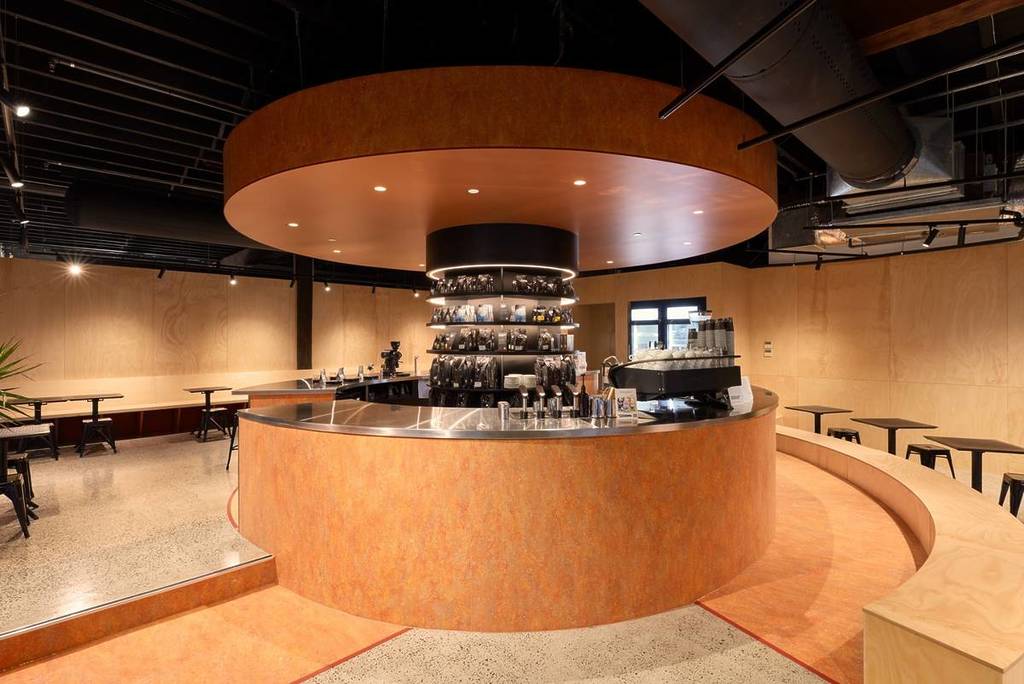 Modern circular Sydney cafe interior at Toby's Estate with a sleek central coffee bar and warm wood finishes