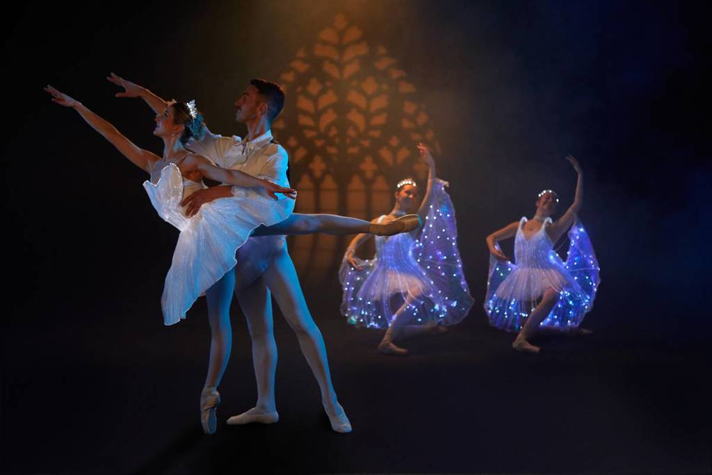 Four ballerinas dancing in luminous costumes at Ballet of Lights