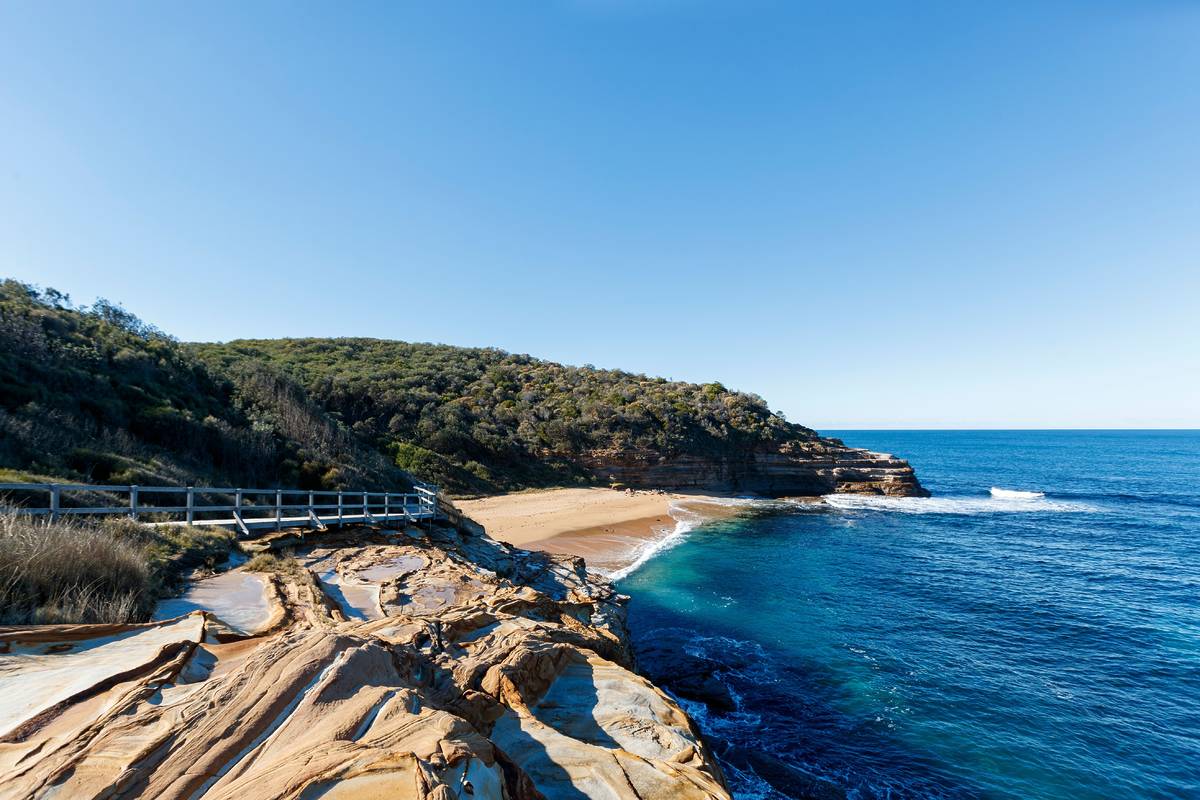Clifftop coastal walk in Bouddi National Park overlooking turquoise waters and a secluded beach