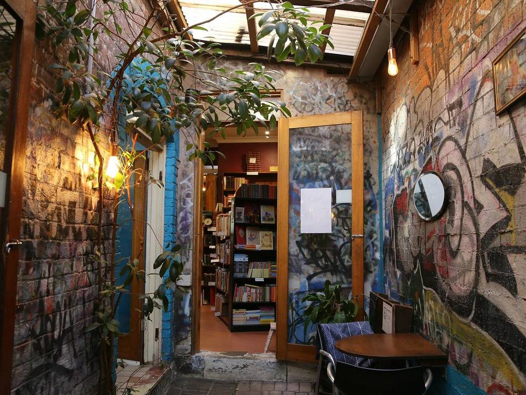 Leafy courtyard entrance at Sappho Books in Glebe, with graffiti walls and cosy bookshop interior