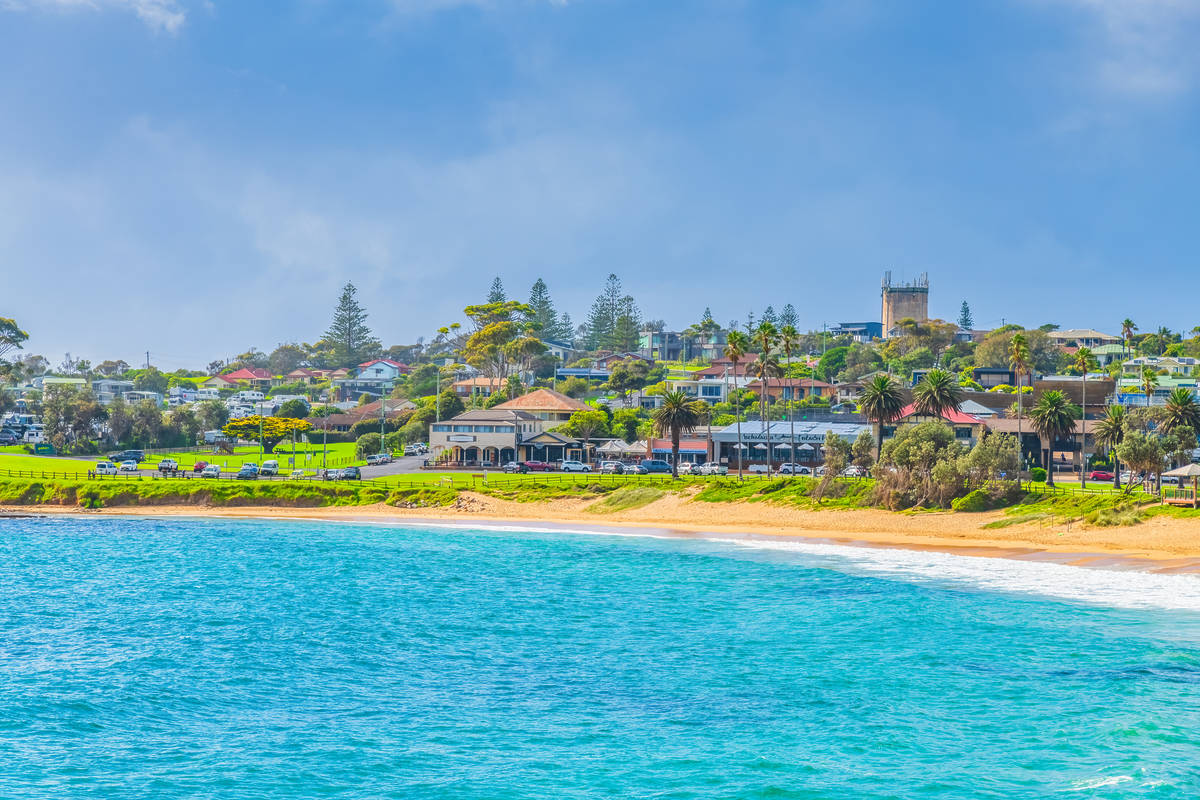 Bermagui town centre overlooking a sandy beach and vivid blue ocean on the Sapphire Coast
