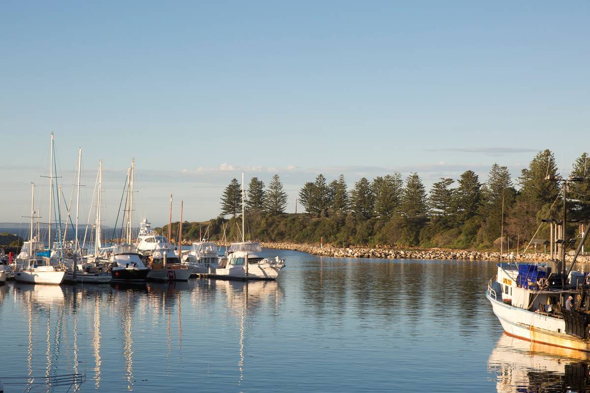 Fishing boats and yachts moored in the calm waters of Bermagui Harbour at sunset