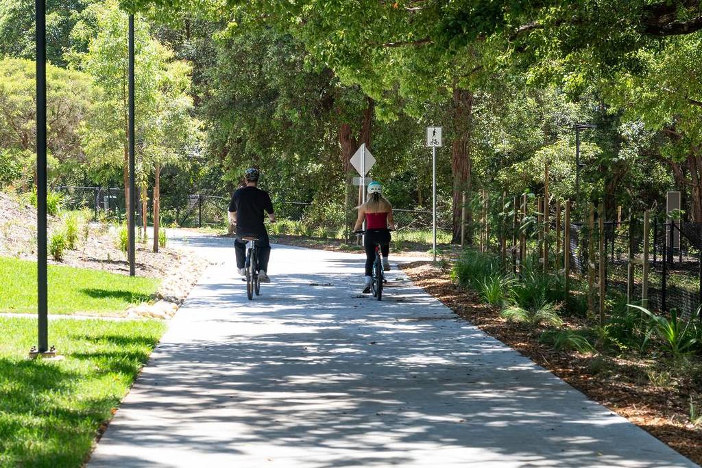 Cyclists riding along the leafy shared walking and cycling path, MetroWay, in Sydney's inner west
