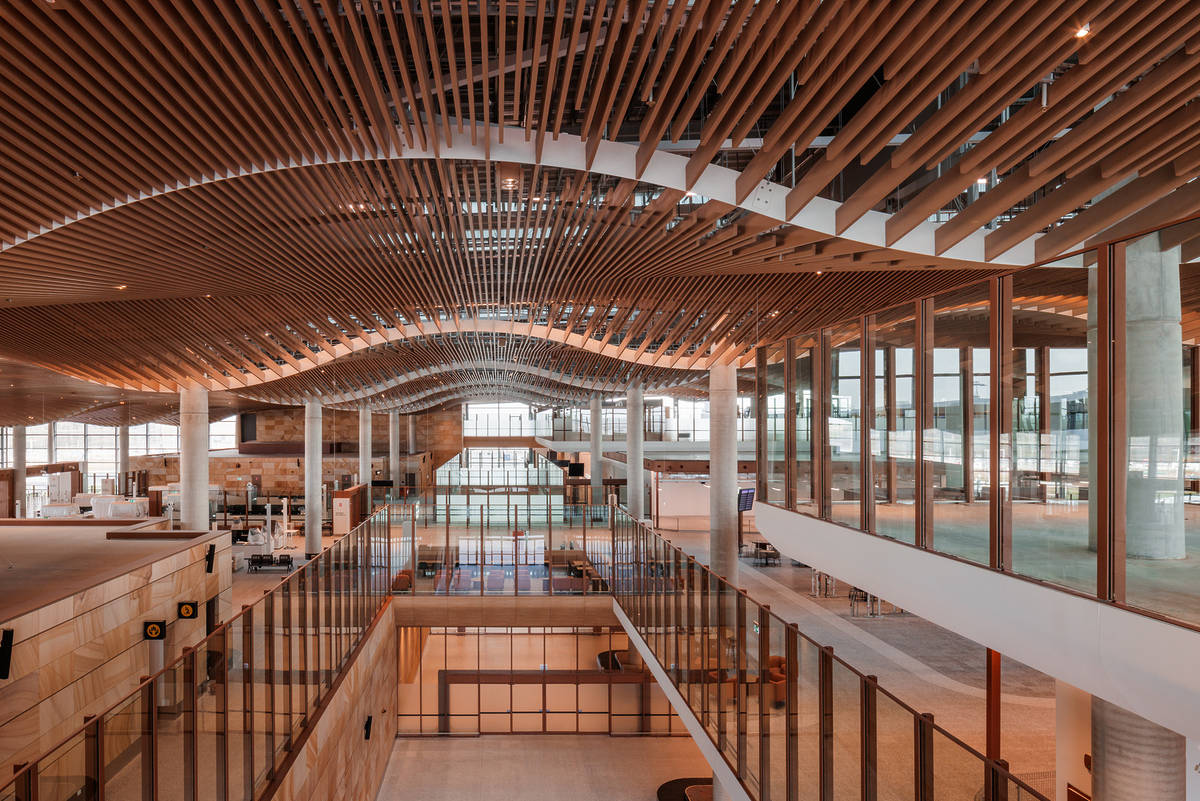Wide interior view of Western Sydney International Airport terminal showcasing the curved timber ceiling and open passenger spaces