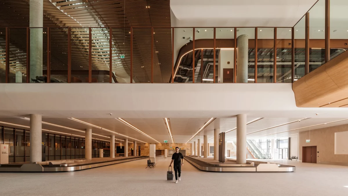 Interior of Western Sydney International Airport showing the baggage reclaim area with a traveller walking past the luggage carousels
