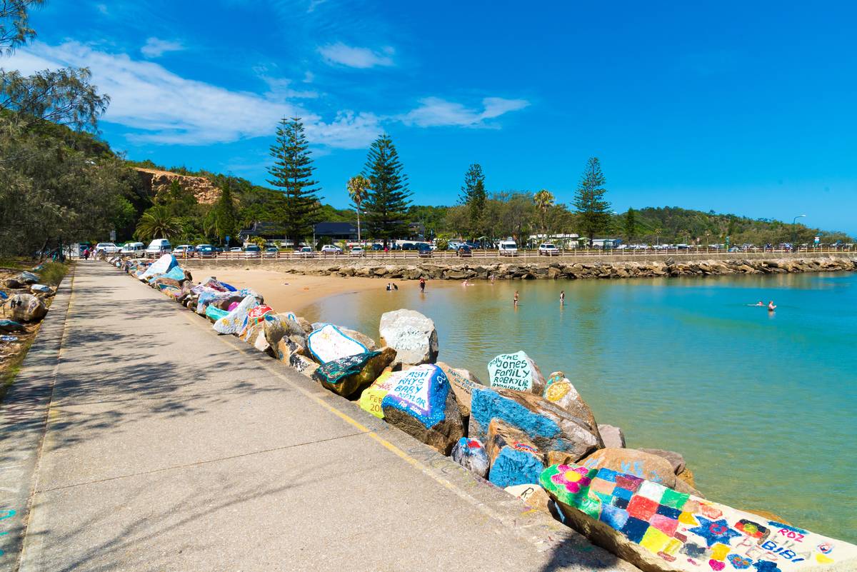 Painted rocks along the V-Wall overlooking a calm beach and turquoise water in Nambucca Heads