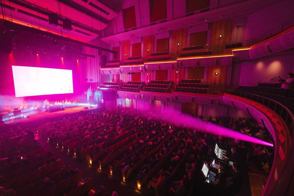 Audience gathered inside City Recital Hall during a Vivid Sydney talk or performance event under pink stage lighting