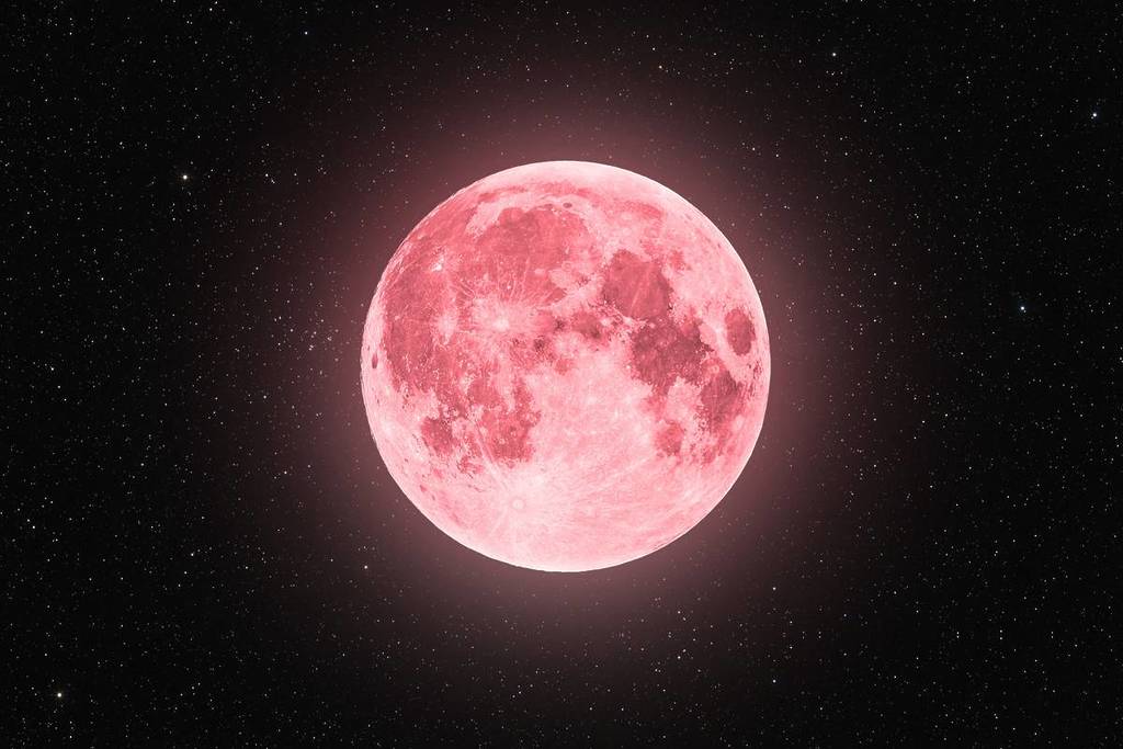 Full moon against a dark night sky, shown with a pink-toned hue and visible surface details