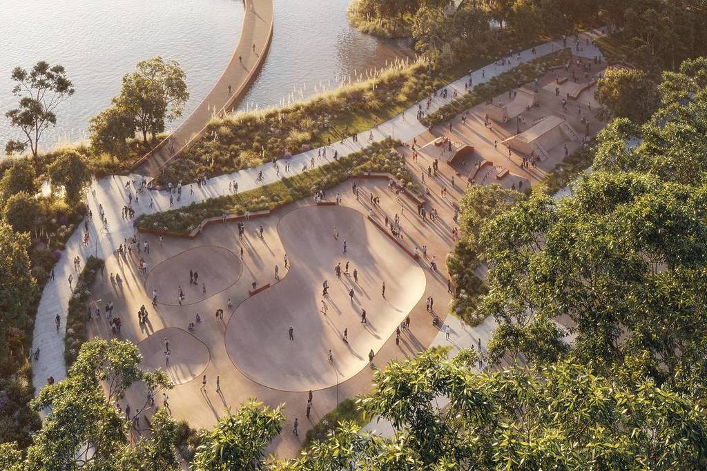 Aerial view of the Warrawong Parklands skatepark with curved bowls, surrounding pathways, landscaped greenery and a boardwalk over the water at sunset