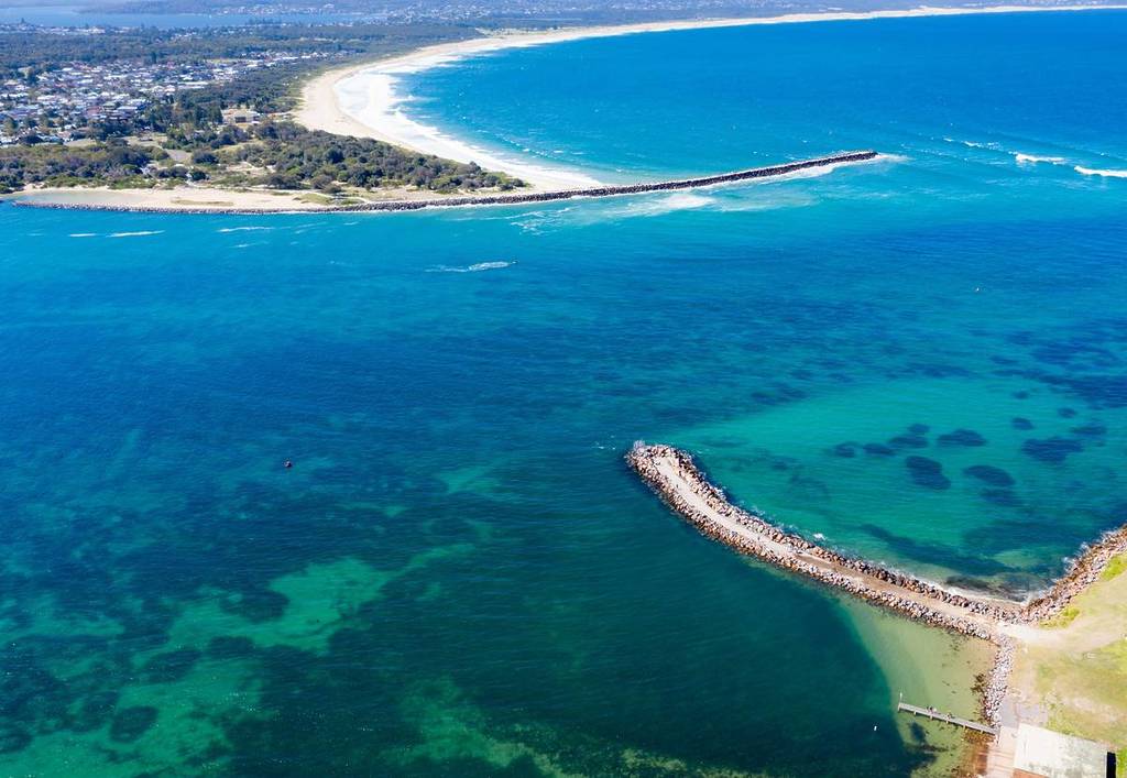 Aerial view of Lake Macquarie's entrance channel and coastline with turquoise water and sandy shoreline