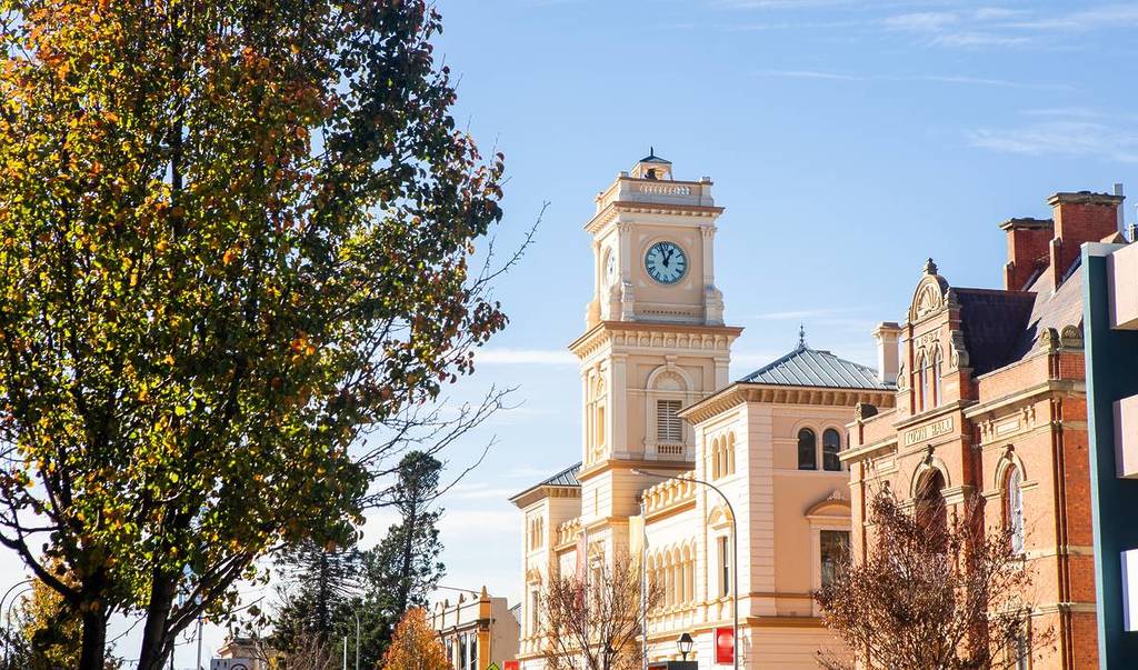 Goulburn Town Hall clock tower framed by autumn leaves under a clear blue sky