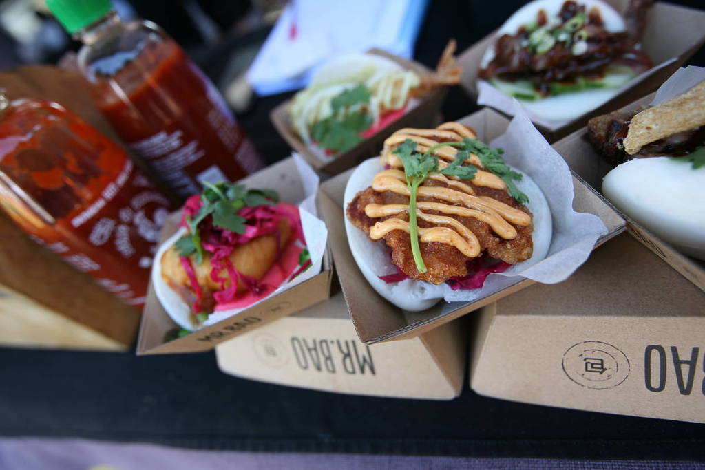 Assorted street food including bao buns and sauces served in takeaway trays at a Sydney market
