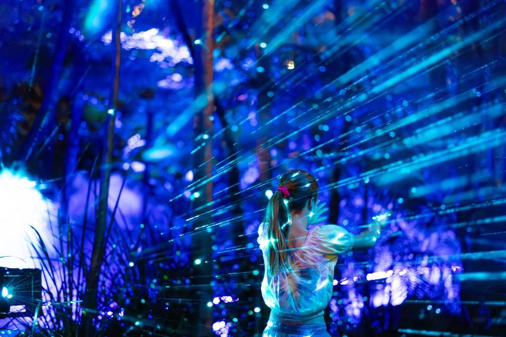 Child interacting with blue laser light installation along the GLOW night trail at Sydney Zoo