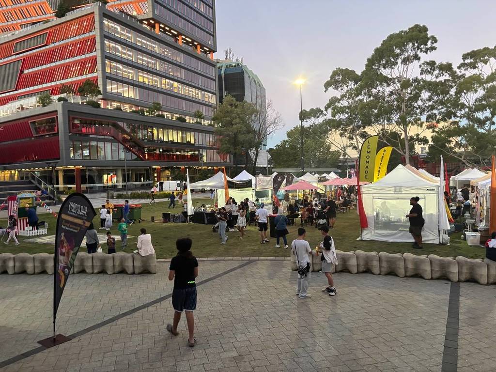 Wide view of food stalls and visitors at Eat Drink Nights market in Bankstown at sunset