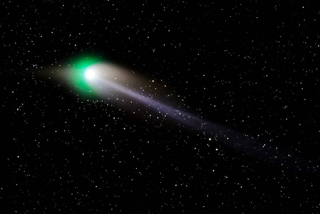 Illustration of a rare green comet glowing blue-green as it passes through space with a long illuminated tail