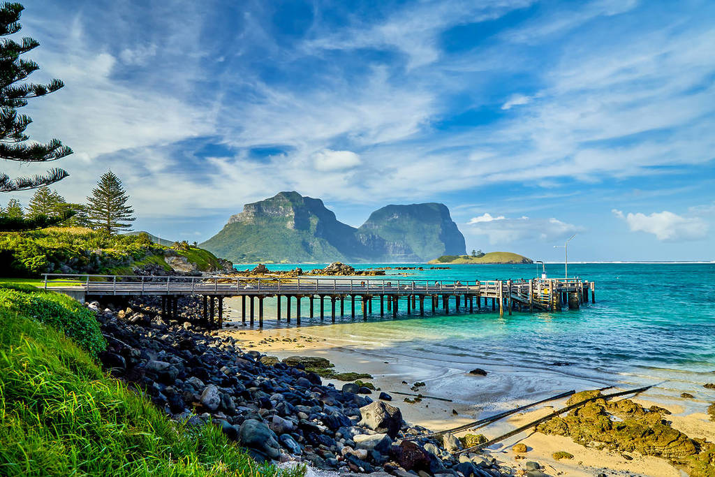 Jetty stretching into clear blue water with Mount Gower and Mount Lidgbird in the background on Lord Howe Island