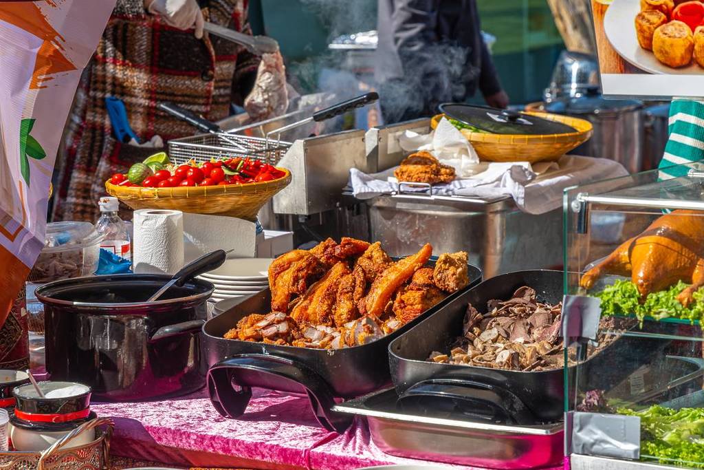 Street food stall serving hot fried dishes and fresh ingredients at an outdoor market