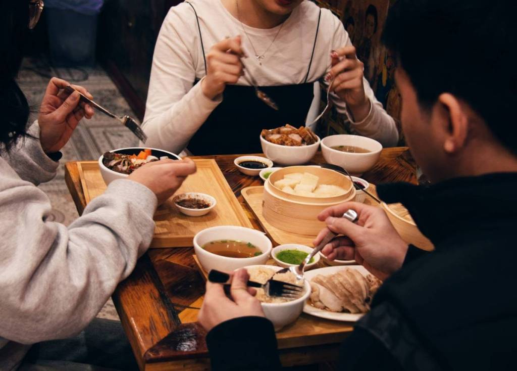 Diners sharing several Thai dishes at Khao Man Kai restaurant in Haymarket
