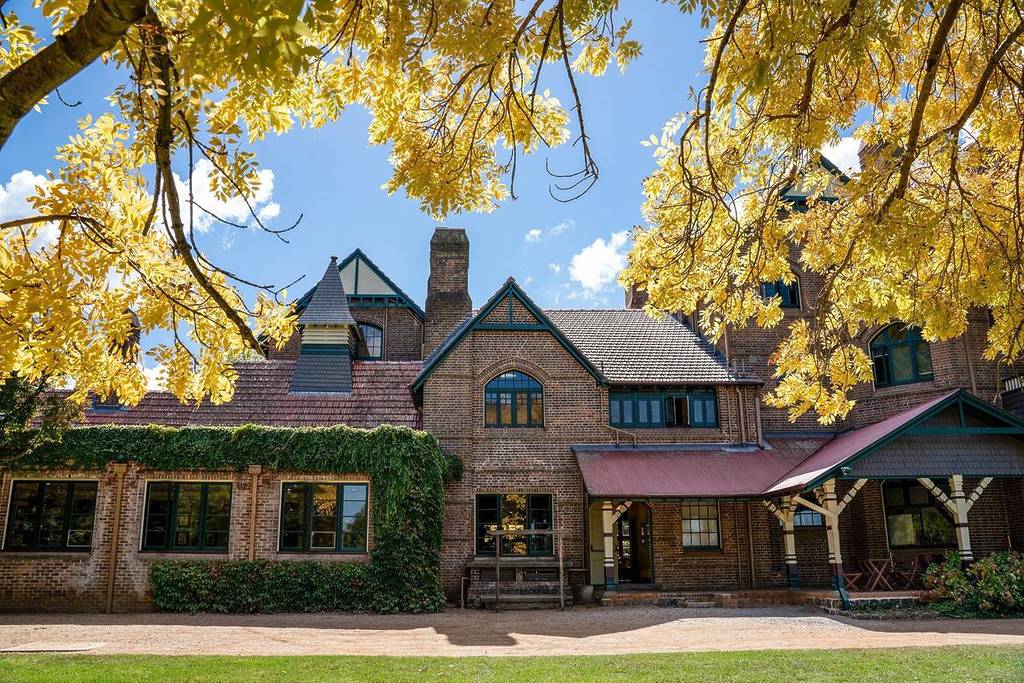 Historic University of New England building framed by bright yellow autumn foliage in Armidale