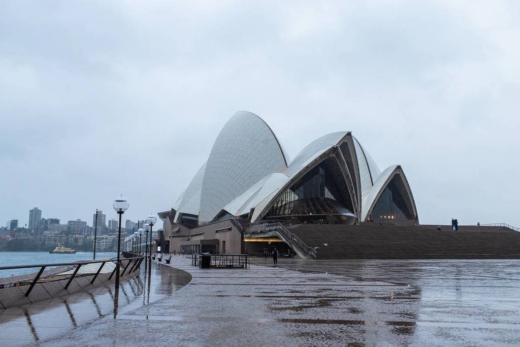 Sydney Opera House in heavy rain with wet pavements and overcast skies along the harbour foreshore