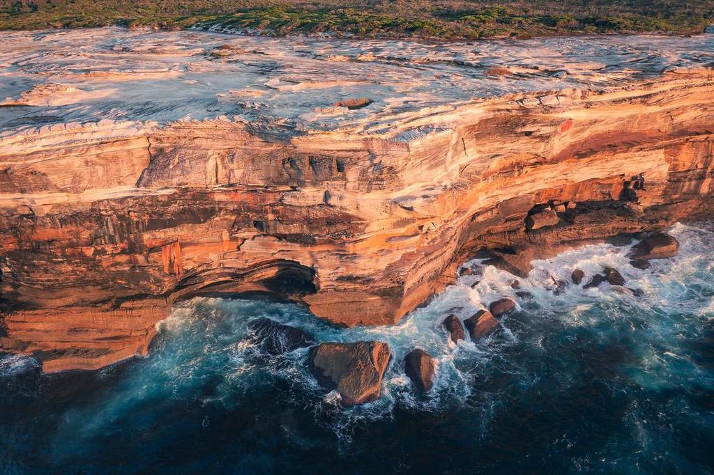 Dramatic sandstone cliffs and turquoise ocean waters along the Cape Baily Walking Track in Sydney
