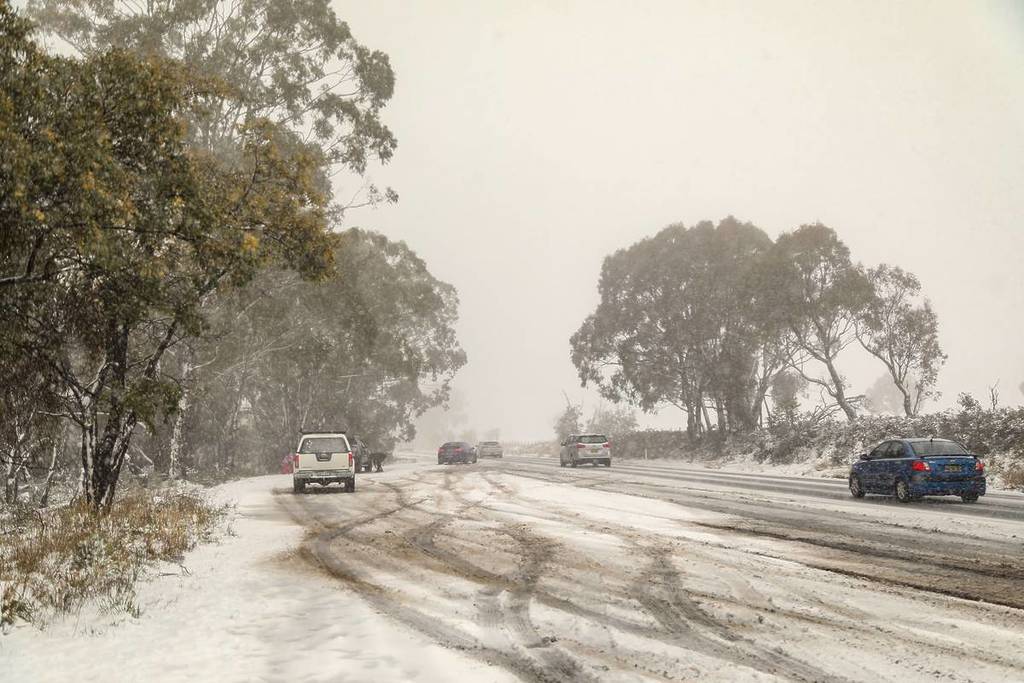 Snow-covered road in the Snowy Mountains with cars travelling through wintry conditions during a snowfall