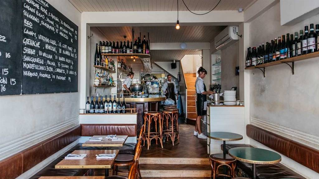 Interior of 10 William Street in Paddington, featuring wine-lined shelves, timber furnishings and an open kitchen