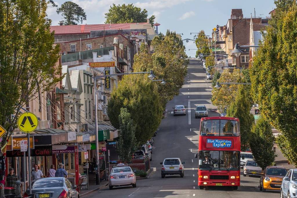 Katoomba's main street lined with heritage buildings, shops and the Blue Mountains Explorer bus travelling through town