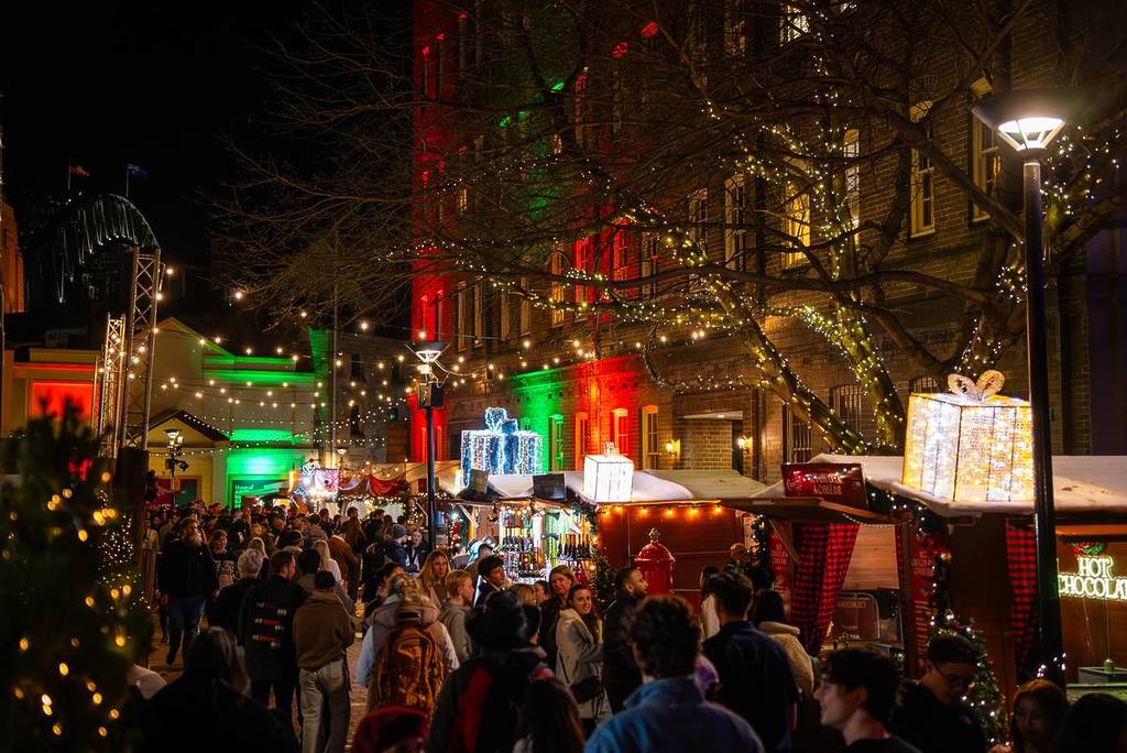 Crowds exploring festive market stalls beneath fairy lights at Christmas in July in The Rocks
