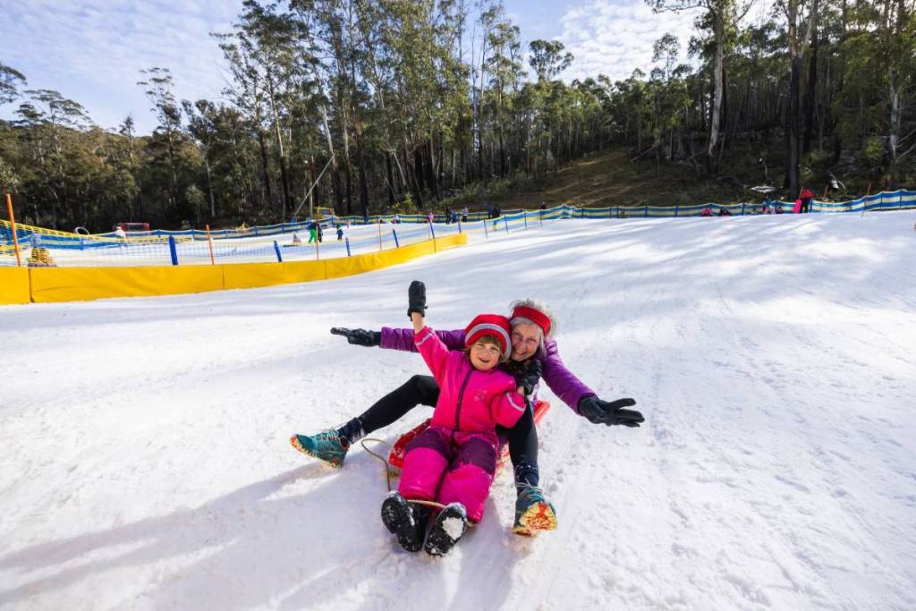 Family enjoying tobogganing and snow play at Corin Forest near Canberra