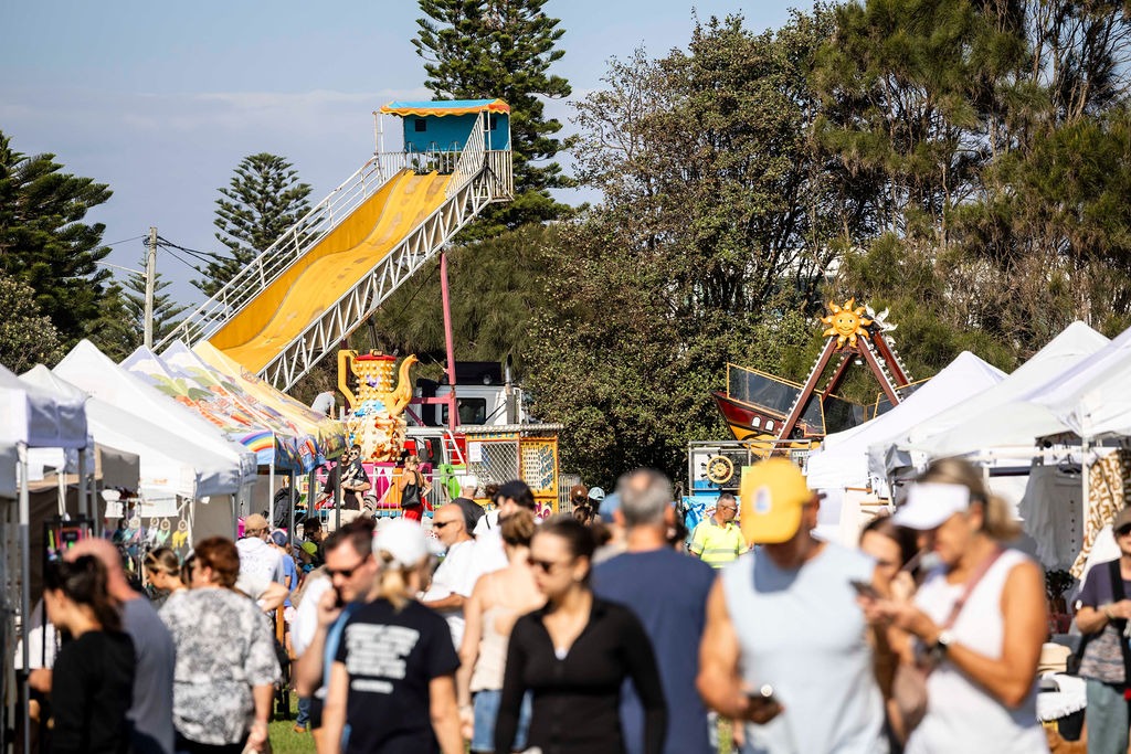 Visitors browse market stalls at the Cronulla Winter Market with family rides in the background