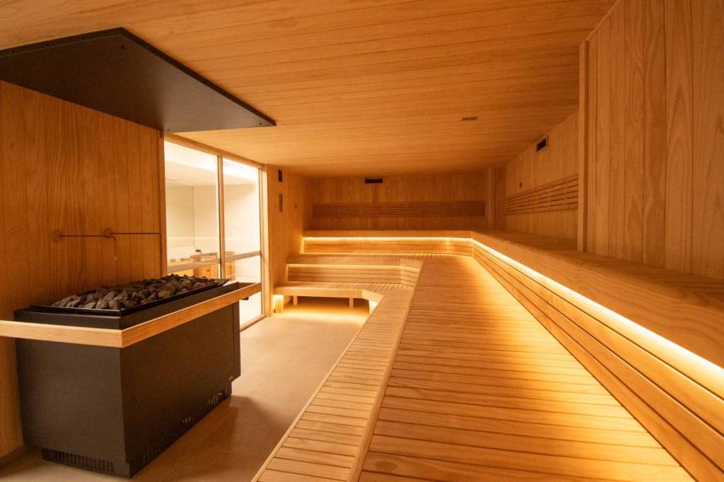 Large traditional Finnish sauna at XtraClubs with tiered timber seating and sauna heater