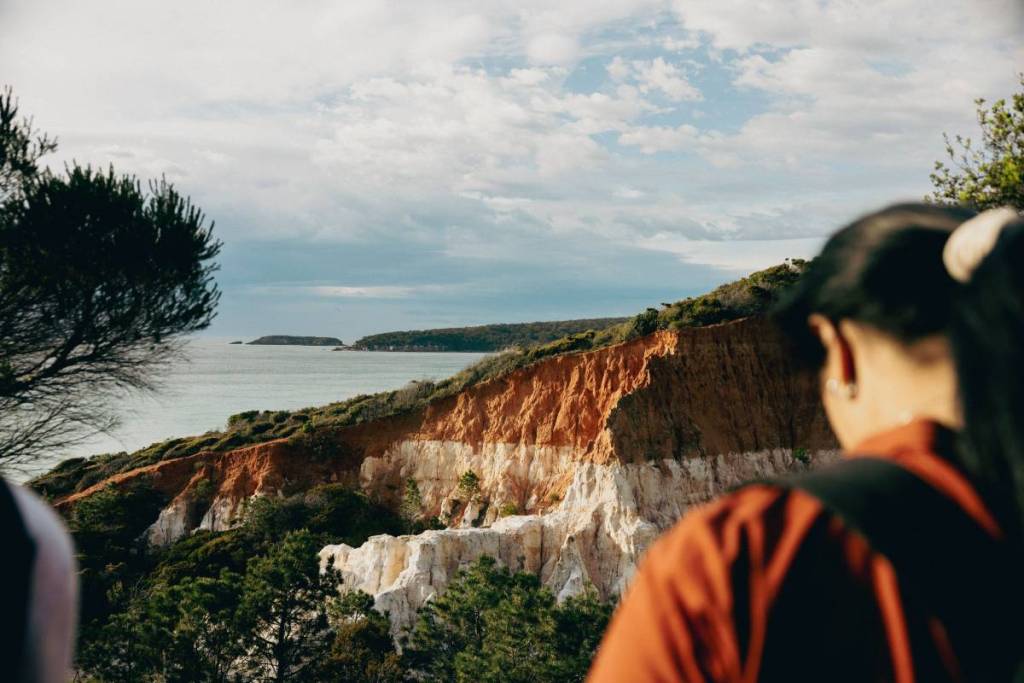 Walkers overlooking the dramatic red and white coastal cliffs on the Light to Light Walk in Beowa National Park