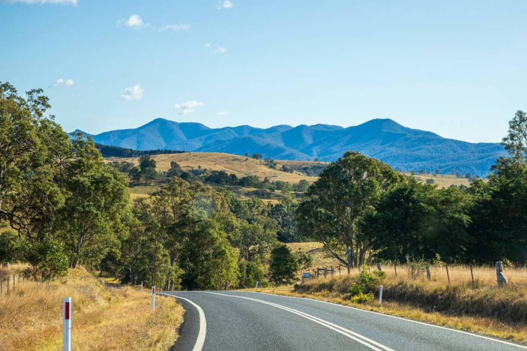 Scenic road winding through the Monaro countryside near Cooma with mountain ranges in the distance