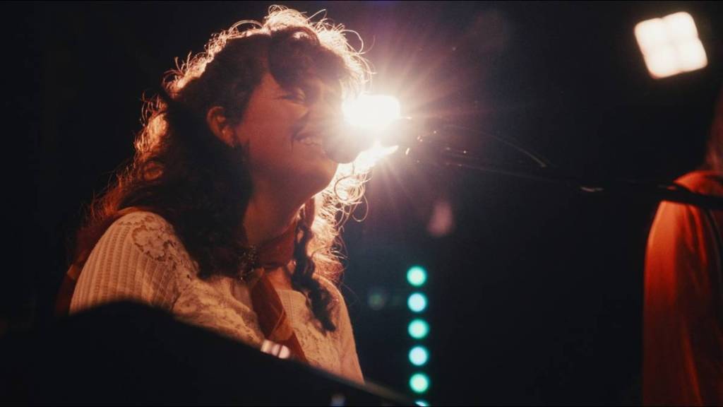 A musician performs on stage under bright lights during a live performance.