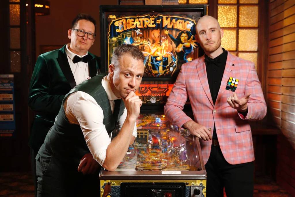 Three magicians next to an arcade machine for Theatre of Magic