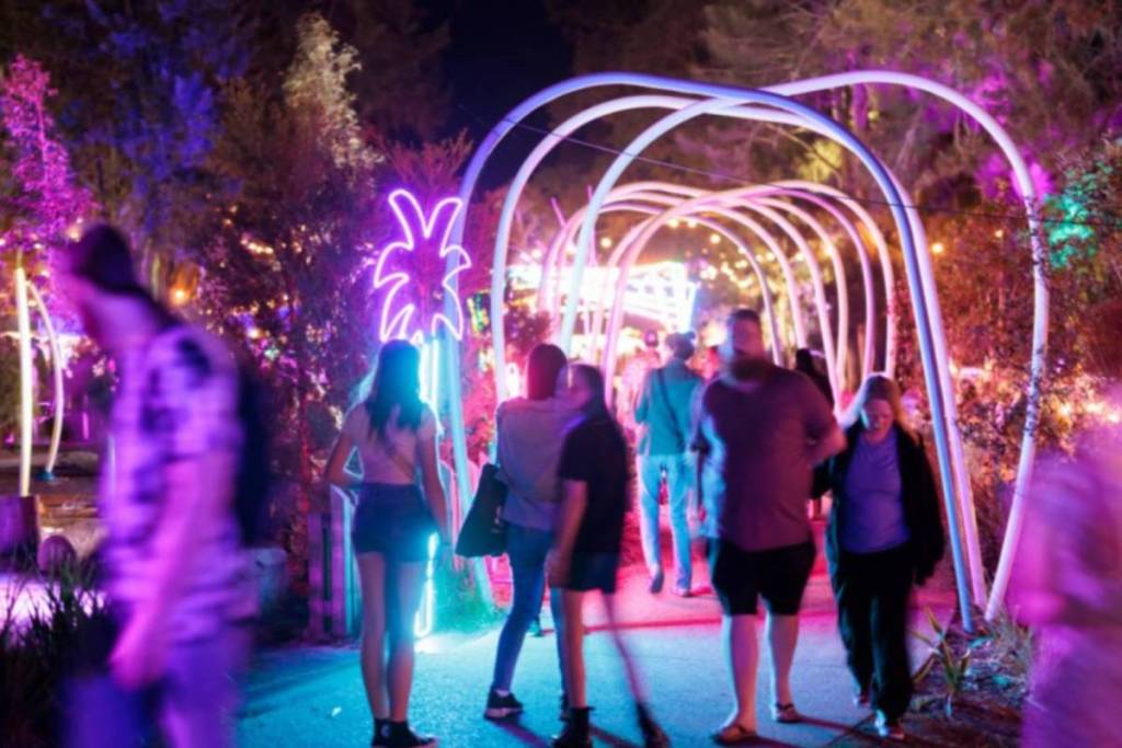 Visitors walking through a colourful illuminated light installation at Real Festival in Penrith