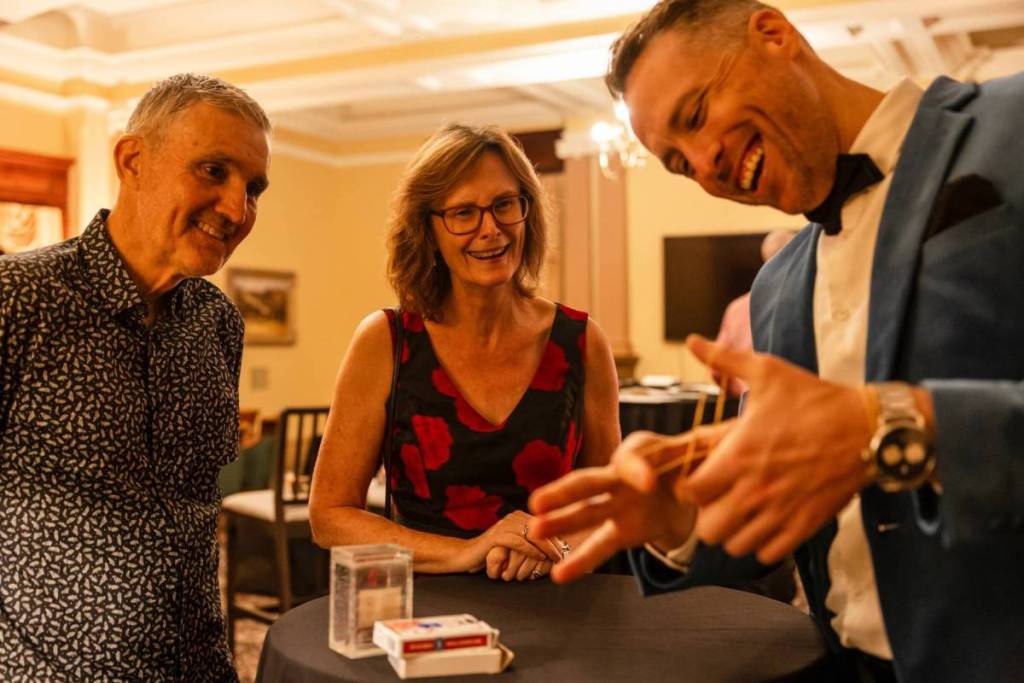A magician doing a card trick for a couple at Theatre of Magic