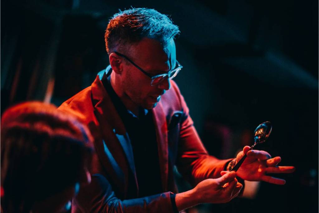 A magician holding a spoon in his hand for a magic trick